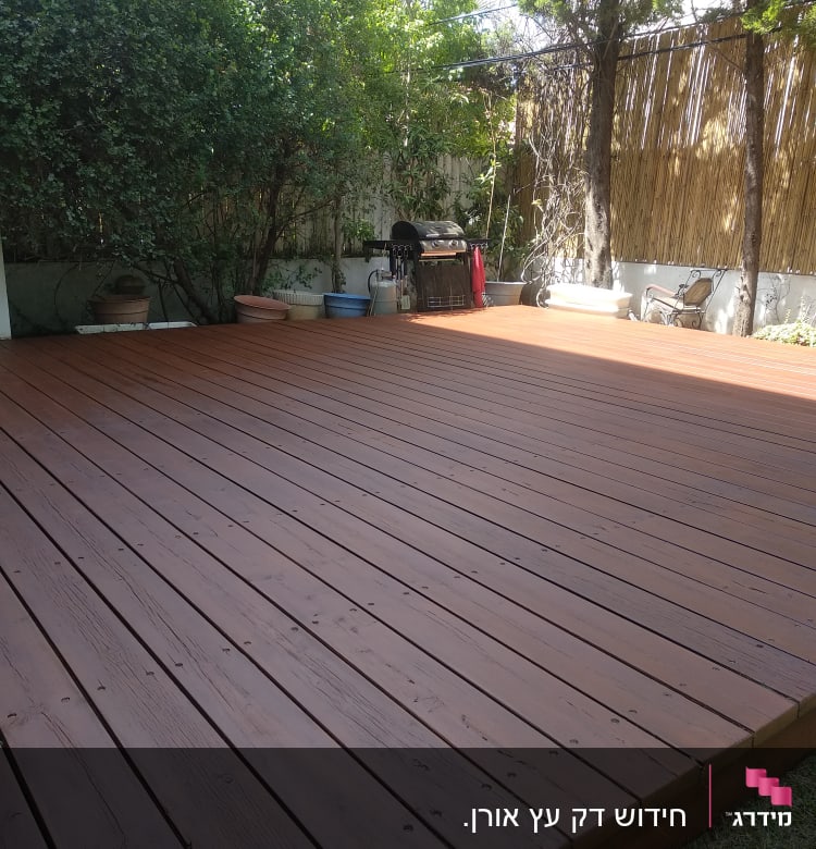 דק עץ בגינה עם עצים וצמחים מסביב